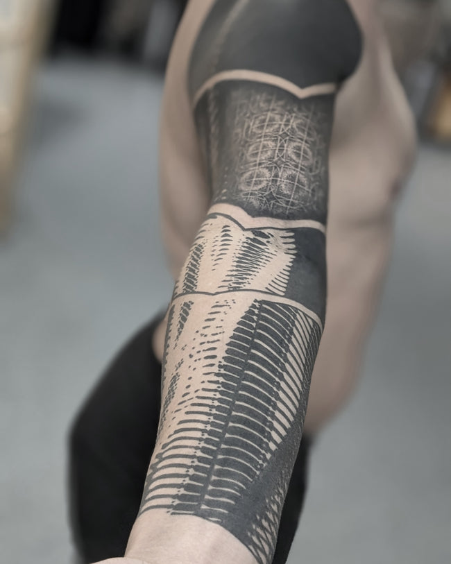 bioorganic industrial tattoo detail – heavy blackwork abstraction inspired by ancient Egyptian motifs, sleeve close-up