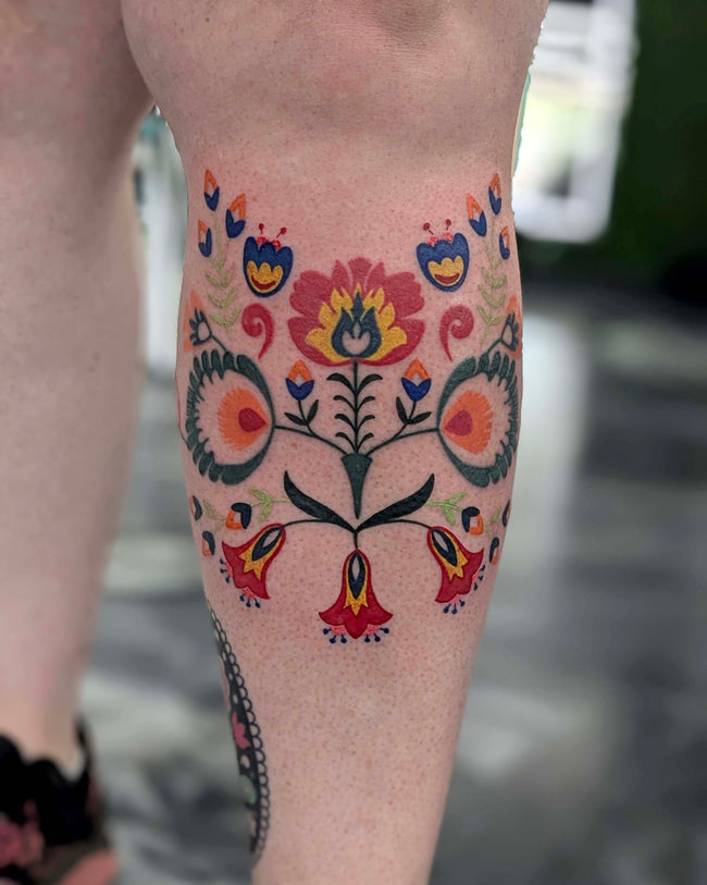 traditional Polish folk flowers tattoo – wycinanka style in full color on leg