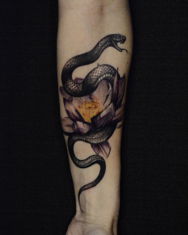 illustrative snake tattoo – black and grey with graphic lotus flower and touch of color on forearm